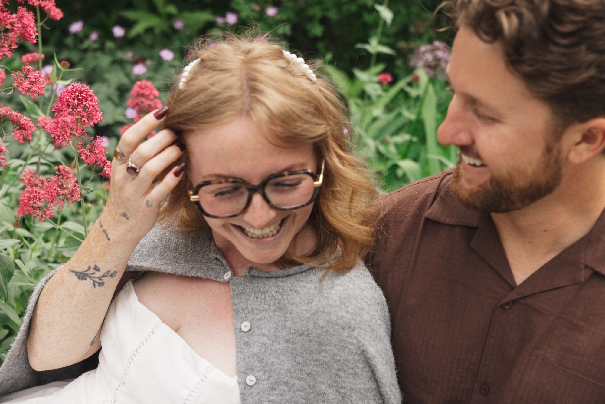 Madison and Evan laughing together among bright pink garden blooms