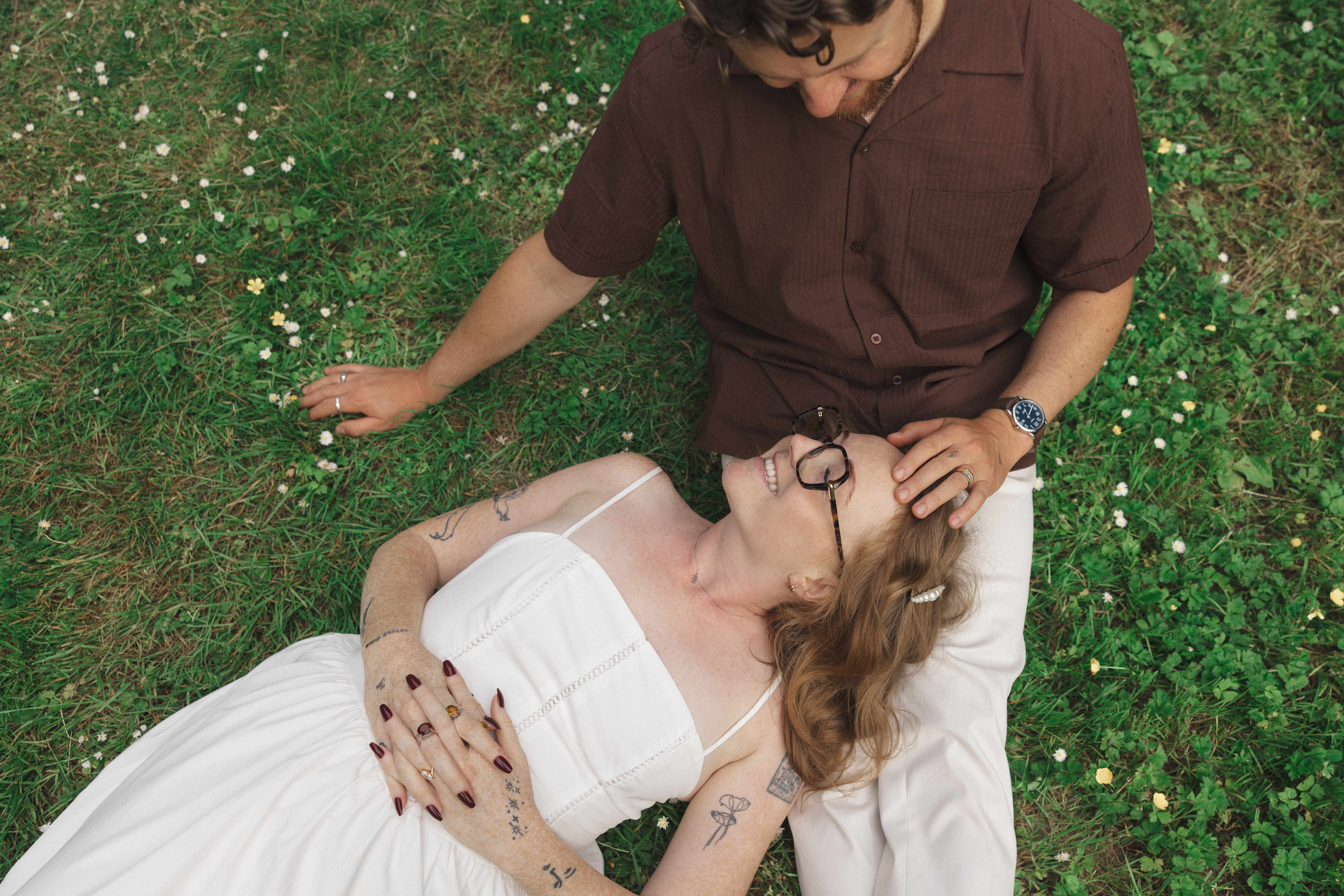 Madison and Evan lying together in a sunny, daisy-dotted lawn